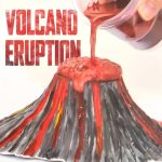 Modell av en vulkan i utbrott med rödaktig lava som rinner från toppen, som illustrerar ett spektakulärt geologiskt fenomen.