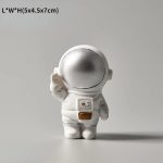 Astronautfigur i vetenskaplig stil, med glänsande silverhjälm och vit dräkt, idealisk för kontorsdekoration eller ett utrymme dedikerat till vetenskap.