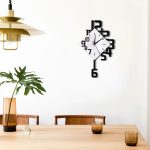 Väggklocka med design med snedställda svarta siffror och vit urtavla, hängande på en vit vägg i en elegant matsal.
