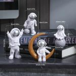 Set med astronautfigurer i vitt med en orange måne, perfekta för vetenskaplig dekoration eller för astronomientusiaster.