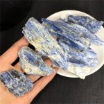 Rå safir med olika nyanser av blått, presenterad i en hand och på en tallrik, idealisk för vetenskaplig dekoration eller mineralinsamling.