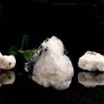 Naturlig vit kvartssten med kristalliska detaljer, tillsammans med en liten grön växt, framhäver mineralets textur och renhet.