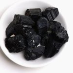 Rå svart obsidian, naturlig sten med glänsande reflektioner, används i dekoration och kristallhealing.