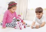 Två barn leker med en interaktiv rosa och vit robot i ett ljust rum, stimulerar deras nyfikenhet och kreativitet genom utbildningsteknik.