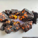 Glödande meteorit med grov yta och ljusa orange fläckar, som illustrerar ett spektakulärt naturligt fenomen.