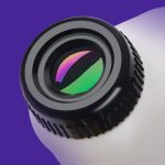 Vetenskapligt objektiv med polariserande filter för optiska experiment, monterat på en lila och vit bakgrund, som illustrerar precision och teknik inom optik.