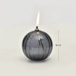 Rund glasvas med tänd ljus, höjd 8 cm, dekoration i vetenskaplig eller modern stil.