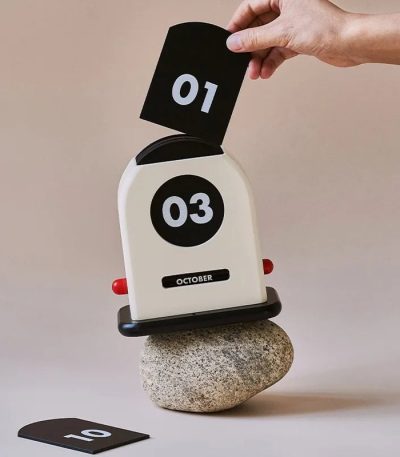 Original kalender i form av en vintage skrivmaskin med digital visning, placerad på en sten, för en vetenskaplig eller retro dekoration.