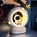 Nattlampa i form av måne med en astronaut och en liten kyckling, idealisk för inredning av barnrum eller som en pedagogisk nattlampa.