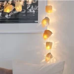 Lampa i naturlig sten med mjukt ljus, perfekt för inredning och att skapa en varm atmosfär i ditt vardagsrum.