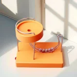 Bollhållare i metall och orange plast, dekorativt vetenskapligt objekt för kontor eller inredning, som förenar modern design och vetenskapliga element.