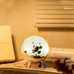 Skrivbordslampa i form av en planet med lysande yta och svarta detaljer, idealisk för vetenskaplig inredning eller en inspirerande arbetsyta.