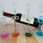 Set med laboratorieflaskor i glas med färgade provrör, placerade på en träyta, som framkallar en vetenskaplig och elegant dekoration.