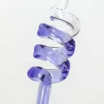 Lila glaspendel i spiralform, hängande med en transparent tråd, som framhäver sin transparens och ljusa reflektioner.