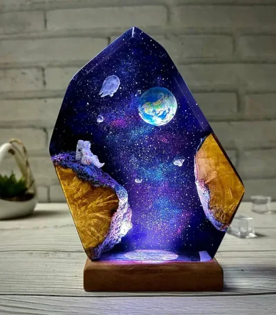 Ljuspanel i resin med rymdscen, planeten Jorden, flytande astronaut, stjärnor och galax, på en träbas, originaldekoration för astronomientusiaster.