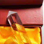 Dekorativt objekt i transparent glas med en elegant geometrisk form, presenterat i en låda med gul satininsida, perfekt för vetenskaplig eller modern dekoration.