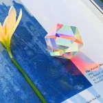 Vetenskapligt objekt i glas med holografisk effekt, placerad på en blå yta, som illustrerar ett dekorativt eller experimentellt objekt.