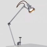 Vintage vetenskaplig skrivbordslampa med ledad arm i metall och belysande glödlampa, perfekt för industriell eller vetenskaplig inredning.