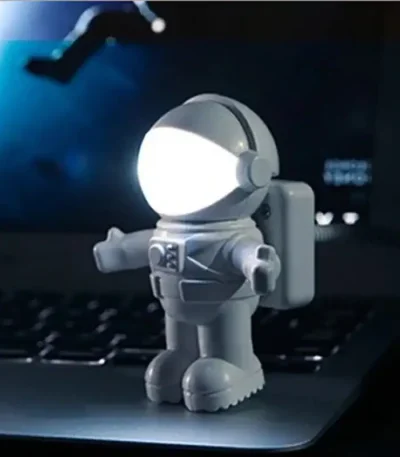 Liten astronautfigur i plast med inbyggd LED-lampa, idealisk för kontors- eller vetenskaplig temadekor, som ger en futuristisk och lekfull touch.