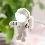 Liten astronautfigur i vit plast, idealisk för kontors- eller vetenskaplig temadekor, som ger en lekfull och pedagogisk touch.