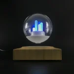 Dekorativ lampa i form av en LED-kula med träbas, idealisk för vetenskaplig eller modern inredning. Avger ett blått och vitt ljus, vilket ger en innovativ touch till ditt hem.