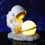 Astronautfigur med lysande planet, rymdtema dekoration för hemmet eller kontoret.