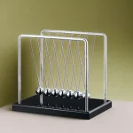 Newton-pendel i metall med hängande kulor, som illustrerar energins bevarande.