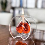 Dekorativ ljushållare i form av ett laboratoriebalon i transparent glas med röd vätska och tänd låga, perfekt för vetenskaplig eller tematisk dekoration.