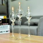 Tre transparenta glasvaser med tända ljus, dekorerar ett träbord i en modern inredning.