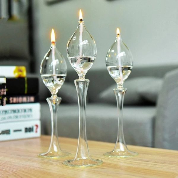 Tre transparenta glasvaser med tända ljus, dekorerar ett träbord i en modern inredning.
