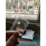 Litet vetenskapligt objekt i transparent glas hålls mellan fingrarna, med ett fönster i bakgrunden. Idealisk för inredning eller vetenskaplig samling.