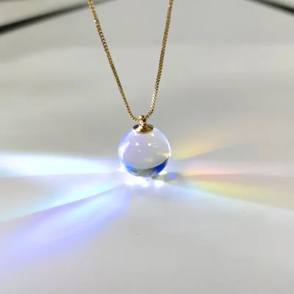 Halsband med transparent glasbollberlock, som fångar ljuset för att skapa en ljus och färgglad effekt. Perfekt för älskare av vetenskaplig dekoration och unika objekt.