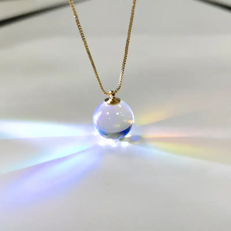 Halsband med transparent glasbollberlock, som fångar ljuset för att skapa en ljus och färgglad effekt. Perfekt för älskare av vetenskaplig dekoration och unika objekt.