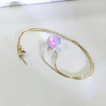 Elegant halsband med iriserande pärlberlock i flera färger, hängande på en fin kedja i guldmetall, perfekt för vetenskaplig dekoration och mode.