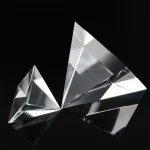 Transparent kristallpyramid med ljusreflexer på svart bakgrund, perfekt för vetenskaplig dekoration eller som samlarobjekt.