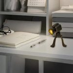 Miniatyrmikroskoplins med belysning på ett laboratoriums skrivbord med böcker och vetenskapligt material.