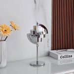 Designerkontorslampa i kromat metall med glänsande finish, idealisk för en modern och elegant inredning i ett arbetsutrymme eller vardagsrum.