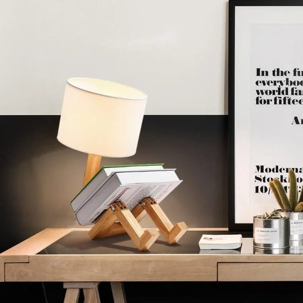 Original skrivbordslampa i form av en robot i trä med tygskärm, perfekt för modern och lekfull dekoration i ett arbetsutrymme eller rum.