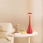 Elegant röd vetenskaplig dekorationlampa på ett bord bredvid en vit soffa, som ger en modern och originell touch till ditt hem.