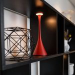 Modern röd vetenskaplig dekorationlampa på svart hylla, som ger en samtida touch till inredningen.