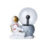 Astronautfigur som sitter bredvid en stenplanet med en kristallkula som representerar en rymdstation eller rymdskepp, idealisk för vetenskaplig eller pedagogisk dekoration.