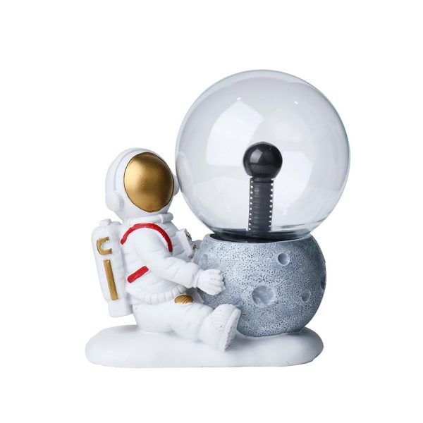 Astronautfigur som sitter bredvid en stenplanet med en kristallkula som representerar en rymdstation eller rymdskepp, idealisk för vetenskaplig eller pedagogisk dekoration.