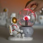 Astronautfigur med elektrisk glob som simulerar ett vetenskapligt experiment, dekor av lekfull och pedagogisk vetenskap.