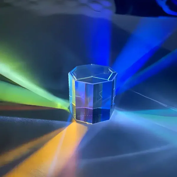 Transparent hexagonalt kristallhänge med färgade ljuseffekter, som projicerar flerfärgade reflektioner på den omgivande ytan.