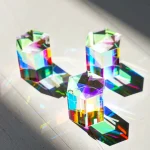 Tre färgade glas kristaller med iriserande reflektioner, som projicerar färgade skuggor på en mörk yta.