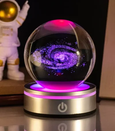 LED-kristallkula med kosmisk spiralvortex i lila och blått, belyst av en rosa och gyllene ljusbas, vetenskaplig och mystisk dekoration.