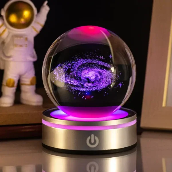 LED-kristallkula med kosmisk spiralvortex i lila och blått, belyst av en rosa och gyllene ljusbas, vetenskaplig och mystisk dekoration.