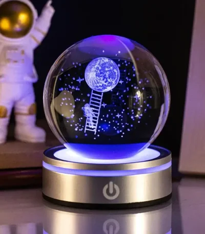 LED-snow globe med månlandskap och astronaut, belyst i blått, idealisk för vetenskaplig och pedagogisk inredning.