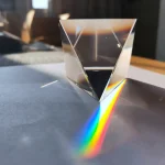 Transparent kristallpyramid som skapar en regnbåge av ljus på ytan. Dekorativt vetenskapligt objekt, perfekt för vetenskaplig eller modern inredning.