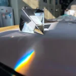 Prismatisk glaspyramid som skapar en regnbåge av ljus på en plan yta, som illustrerar ljusets brytning och spridning.